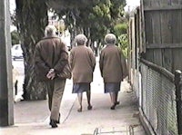 a group of elderly people walking down a sidewalk