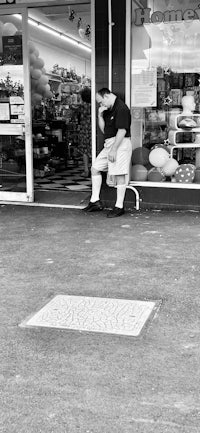 a man sitting on a bench in front of a store