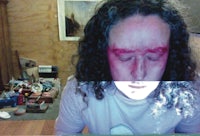 a man with curly hair looking at a computer screen